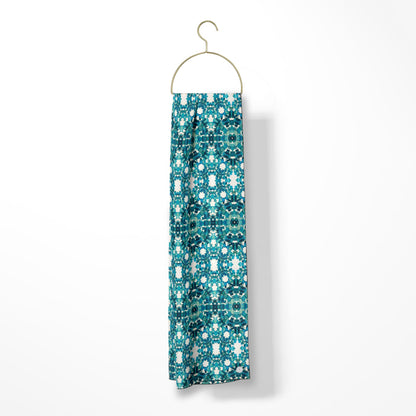 Oblong scarf featuring a teal abstract pattern and hanging from a gold hanger